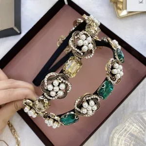 Close-up of Baroque style velvet headband with emerald green gemstones and pearls