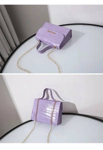 Dettaglio borsa viola a trama coccodrillo con logo dorato e tracolla a catena
