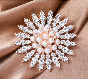Macro shot of snowflake pearl brooch with sparkling rhinestones on brown silk fabric