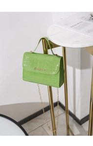 Dettaglio della mini borsa verde brillante con motivo coccodrillo e catena d'oro