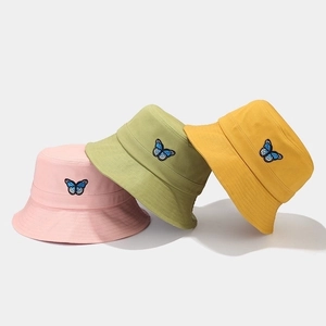 Pastel cotton bucket hats in pink, green, and yellow with blue butterfly embroidery