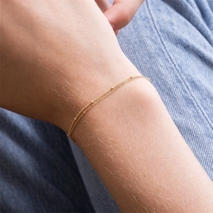 Close-up of gold double-layered chain bracelet with bead accents on a wrist