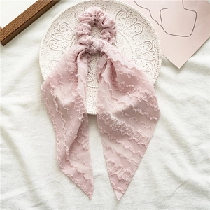 Detail of pink lace ribbon scrunchie with wavy texture on a decorative white plate