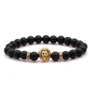 Macro detail of black matte beaded bracelet featuring a golden lion head and crystal rings