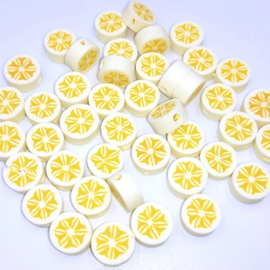 Detailed view of 10mm white polymer clay beads with yellow lemon pattern and center holes