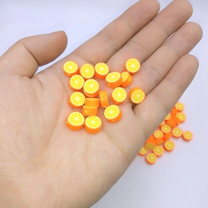 Close-up of handmade orange slice polymer clay beads held in hand for DIY jewelry making