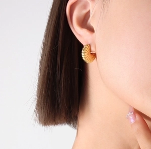 Polished 18K gold plated stainless steel fan-shaped ribbed earrings on female model