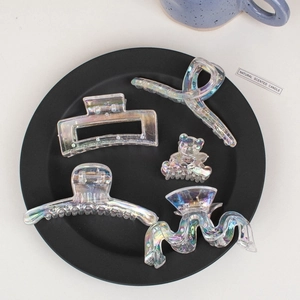 Iridescent laser hair claws in various shapes displayed on a black decorative plate