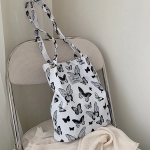 Detail of canvas tote bag featuring black butterfly prints and branded woven label