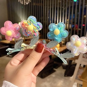 Close-up of four floral hair clips with sequins and plush balls in various colors