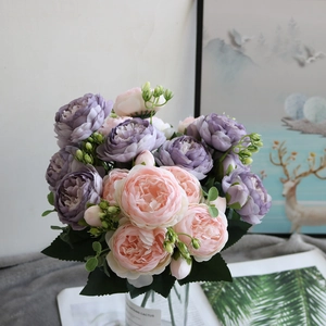 Close-up of purple and pink silk peony flower arrangement in a glass vase for home decor
