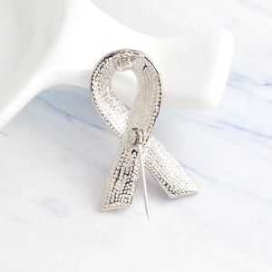 Back view of silver ribbon brooch showing textured metal surface and secure pin closure
