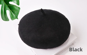 Dettaglio del basco in lana nera con piccola coda decorativa su sfondo bianco