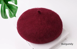 Dettaglio della trama del berretto in lana rosso vino con piccolo stelo sulla parte superiore