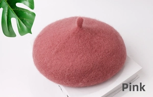 Primo piano di un basco in lana rosa antico con trama morbida e foglia decorativa