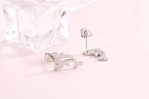 Close-up of polished silver fish stud earrings with a minimalist dolphin design
