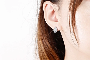 Close-up of minimalist silver bee stud earring in titanium steel on a model's ear