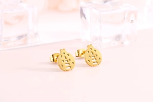 Detailed view of dainty gold-plated ladybug stud earrings on a clean pink background