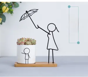 Detail of Nordic iron ceramic planter with umbrella man design on a wooden base