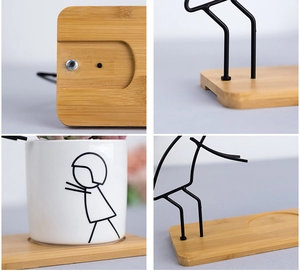 Close-up of minimalist ceramic planter with iron stick figure stand and bamboo base