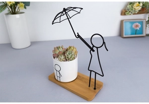 Detail view of the black metal umbrella girl stand with ceramic pot and bamboo tray