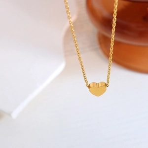 Vista macro de un colgante de corazón de oro pulido en collar minimalista de cadena O