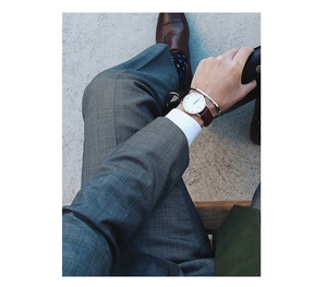 Close-up of a silver minimalist open cuff bracelet paired with a brown leather watch