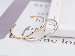 Detailed close-up of rose gold and silver open bangles with geometric faceted finish
