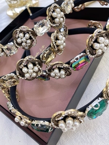 Gros plan d'un serre-tête baroque avec cristaux émeraude, perles et fleurs dorées