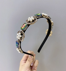 Détail d'un serre-tête baroque avec strass colorés et perles blanches sur base en métal doré