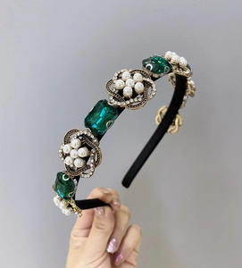Détail d'un serre-tête baroque aux pierres émeraudes et perles sur cadre doré