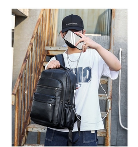 Detail of vintage black leather backpack showing USB charging port and side pocket on stairs
