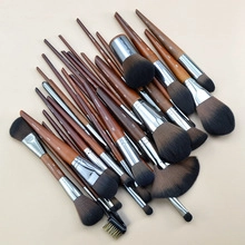 Flat lay of professional makeup brushes with wooden handles on a beige background