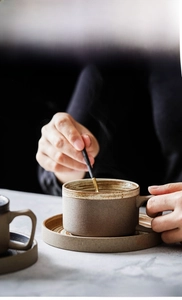 Detailed view of a coarse pottery coffee cup with rustic texture and gold spoon