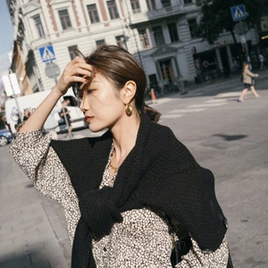 Gros plan d'un mannequin portant des boucles d'oreilles dorées avec une chemise fleurie chic