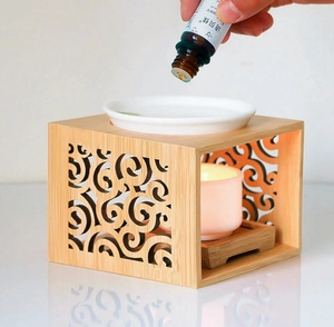 Bamboo wax warmer detail with hand dripping essential oil into a white ceramic dish