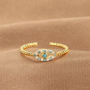 Adjustable gold evil eye ring with blue stones on a luxury brown silk background
