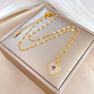 Luxury gold heart pendant necklace with purple gemstone and crystals on jewelry box