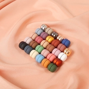 Magnetic scarf pins in various matte and metallic colors on pink silk background