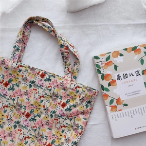 Detailed close-up of floral cotton tote bag with vintage pattern on a white fabric background