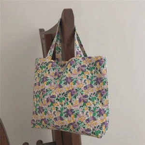 Detail of floral cotton canvas tote bag with yellow and purple flowers on a wooden hanger