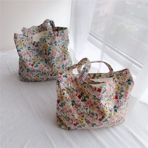 Detail of floral cotton canvas tote bags with delicate flower patterns on white surface