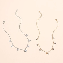 Detail of silver and gold butterfly pendant necklaces with adjustable chains on beige surface