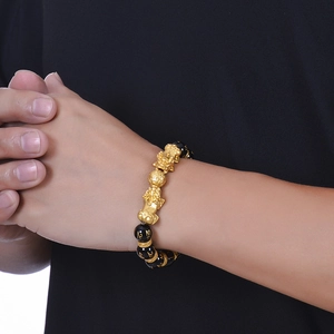 Close-up of black agate beads with golden Pixiu and Six-Syllable Mantra carvings on a bracelet