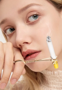 Close-up of golden bee cigarette holder ring worn on hand with soft lighting