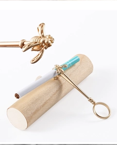 Macro detail of a golden bee cigarette holder ring showing the metallic clip and design