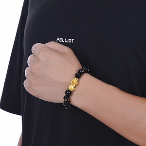Natural black agate Pixiu bracelet with gold mantras, shown on wrist against dark background