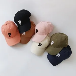 Flat lay of seven colorful cotton kids baseball caps with embroidered P letter detail