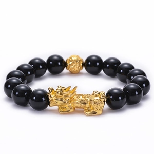 Vue détaillée des perles d'obsidienne noire et du Pixiu doré sur le bracelet feng shui