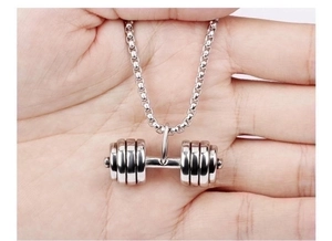 Macro view of a silver dumbbell pendant held in hand showing fine stainless steel details